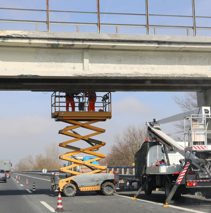 Men at work on a bridge over a highway