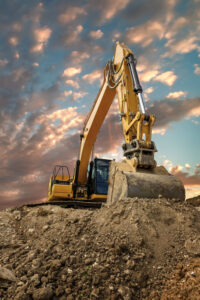 Crawler excavator during earthmoving works on construction site at sunset