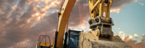 Crawler excavator during earthmoving works on construction site at sunset