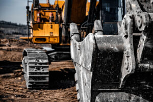 Yellow excavator steel bucket working on construction open mining site.