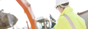 Supervisor using walkie-talkie at construction site against clear sky