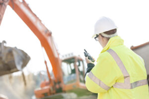 Supervisor using walkie-talkie at construction site against clear sky