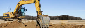 A powerful caterpillar excavator digs the ground against the blue sky. Earthworks with heavy equipment at the construction site